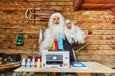 Man dressed as a yeti holding a snowcone behind a megatank printer